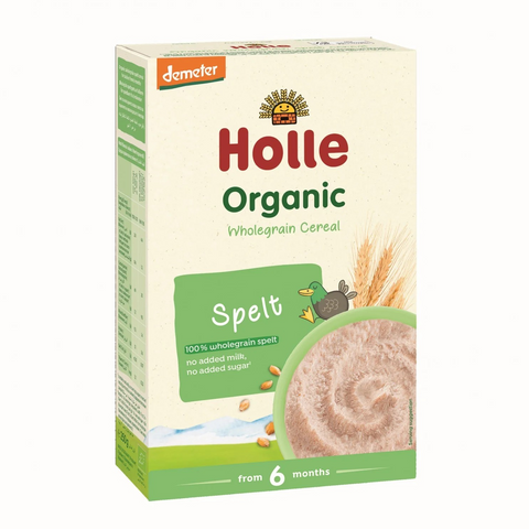 A box of Holle Organic Wholegrain Cereal in the Spelt flavor, designed for babies from 6 months. The packaging is cream-colored with green and red branding, featuring a bowl of prepared cereal and wheat graphics.