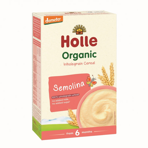 A box of Holle Organic Semolina Wholegrain Cereal for babies from 6 months, featuring a cream-colored box with red and green text, a bowl of cereal, and wheat illustrations.